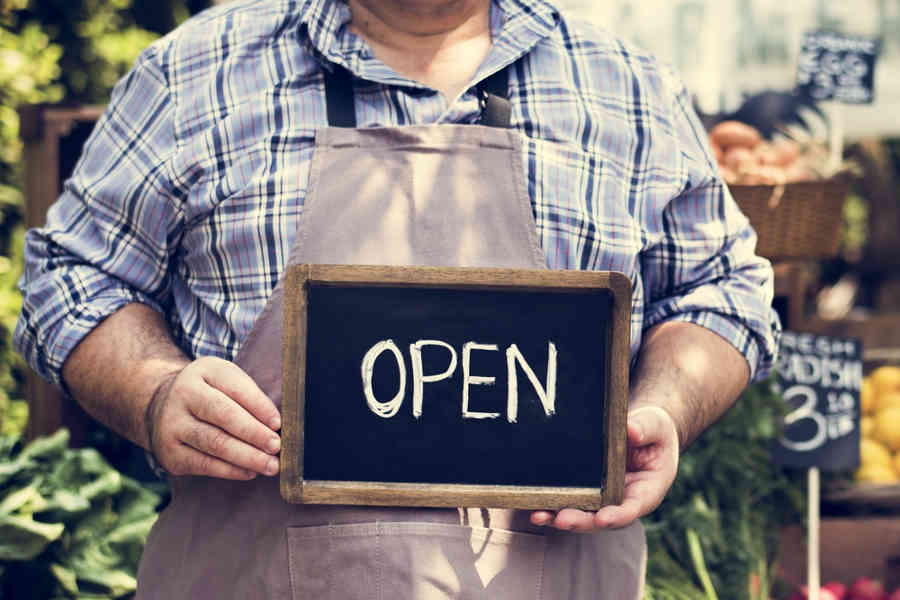 small business owner in Stafford holding OPEN sign